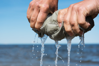 Squeezing of cloth against blue sky.